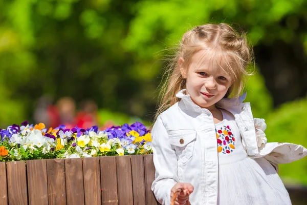 Liten bedårande flicka med blommor i tulpaner trädgård — Stockfoto