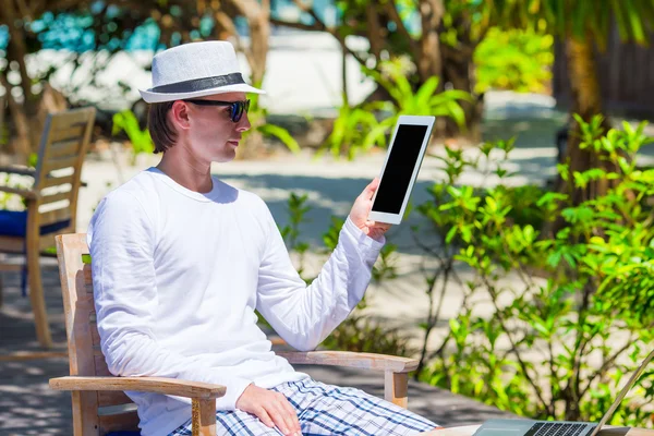 Jongeman met tablet pc op tropisch strand — Stockfoto
