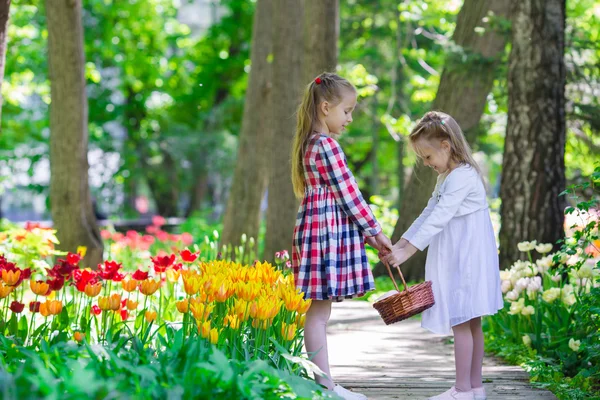 Little adorable girls walking in lush garden of tulips — Stock Photo, Image