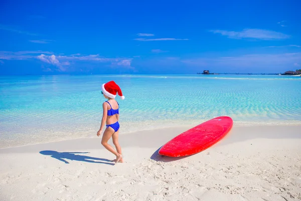 Bambina a Babbo Natale cappello sulla spiaggia durante le vacanze — Foto Stock