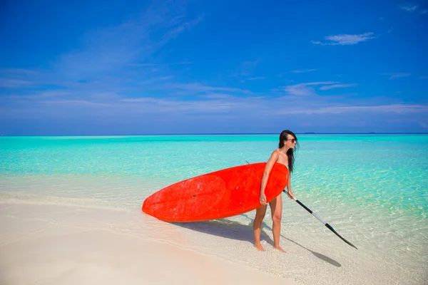 Felice giovane donna surf in spiaggia con una tavola da surf e pagaia — Foto Stock