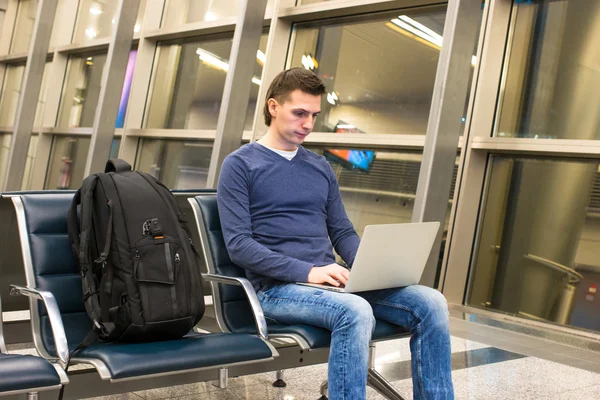Jonge man met laptop en rugzak op luchthaven — Stockfoto