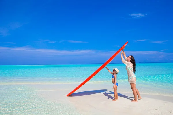 Gelukkige vrouw en meisje op witte strand met surfboard — Stockfoto