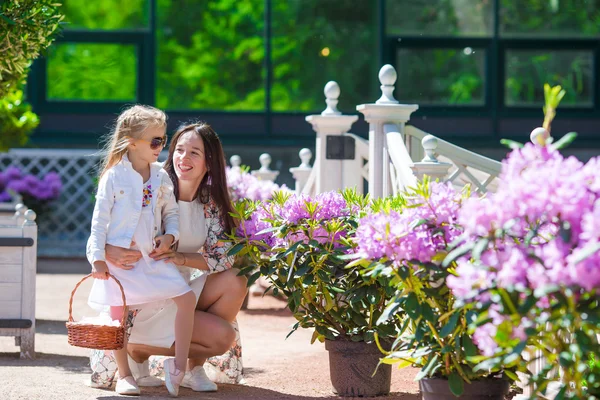 Bedårande liten flicka och ung mamma njuter av varm dag i tulip trädgård — Stockfoto