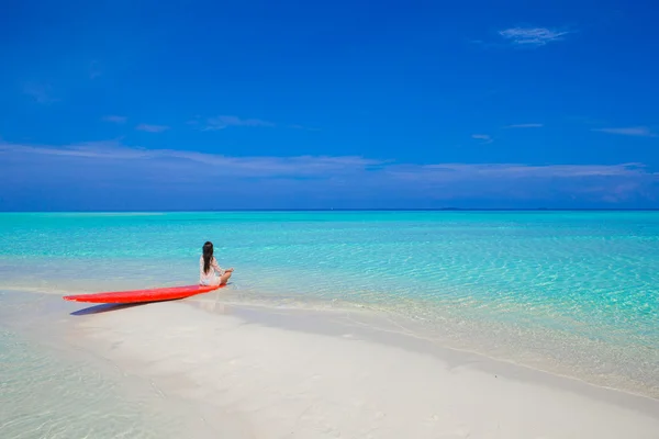 Young surfer woman at white beach on red surfboard — Stock Photo, Image