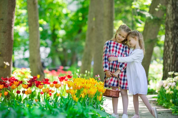 Little adorable girls walking in lush garden of tulips — Stock Photo, Image