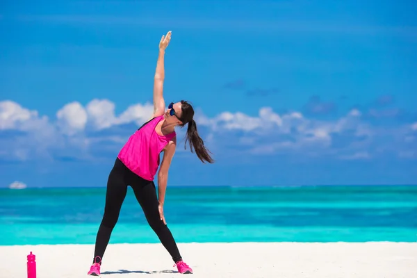 Healthy athlete woman working out doing exercise on tropical white beach in her sportswear — Stock Photo, Image