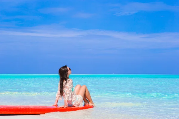 赤いサーフボード上の白いビーチで若いサーファー女性 — ストック写真