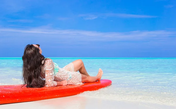 Gelukkig mooie surfer vrouw op witte strand op rode surfplank — Stockfoto