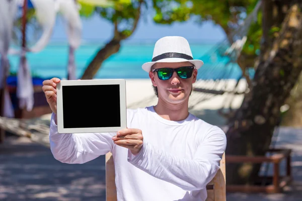 Молодой человек на пляже с планшетным компьютером. Экран цифровой ПК — стоковое фото