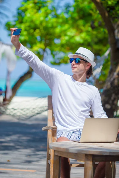 Young man make a photo on cell phone at tropical beach — Stock Photo, Image