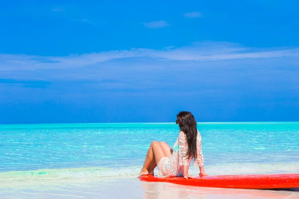 Young surfer woman at white beach on red surfboard — Stock Photo, Image