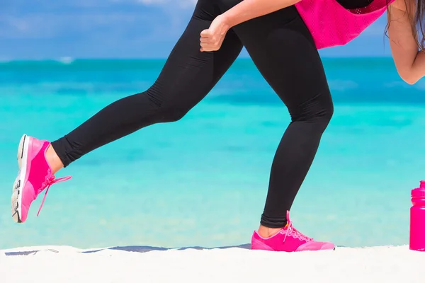 Primeros planos de las piernas femeninas zapatos de running rosa en la playa de arena blanca — Foto de Stock