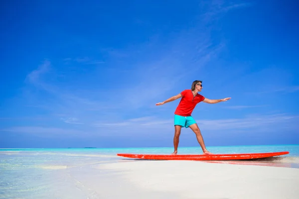 Glücklicher junger Mann übt Surfposition auf Surfbrett — Stockfoto