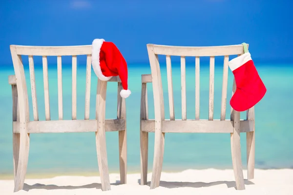 Red Christmas stocking and Santa Hat on chair at tropical white beach — Stock Photo, Image