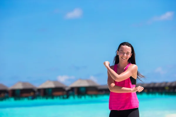 Tropikal beyaz plaj üzerinde egzersiz yaparak çalışan sağlıklı sporcu kadın — Stok fotoğraf