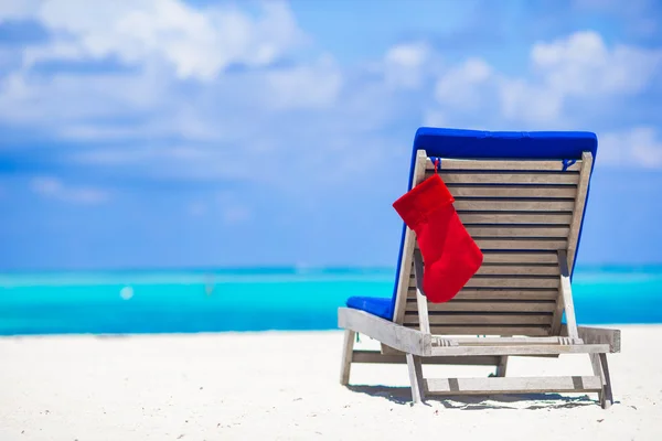 Sun chair longue with red Christmas stocking on tropical white beach and turquoise water — Stock Photo, Image