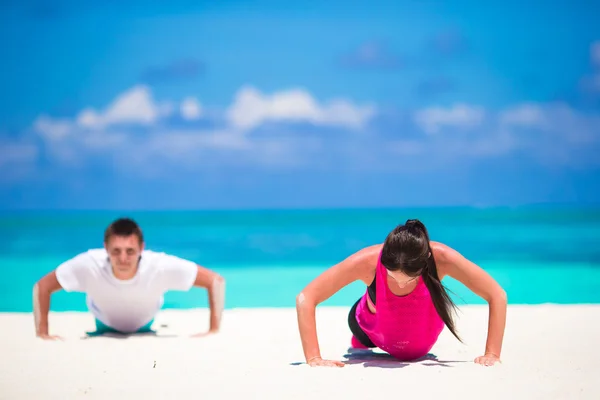 Para młoda fitness robi pompki podczas odkryty krzyż trening na tropikalnej plaży — Zdjęcie stockowe