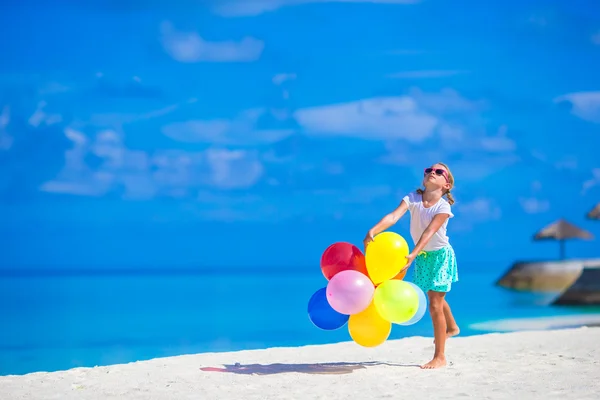 Malá dívka si hraje s barevnými balónky na tropické pláži — Stock fotografie