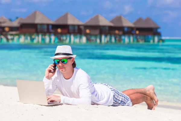Young man working on laptop at tropical beach near water villa — Stock Photo, Image