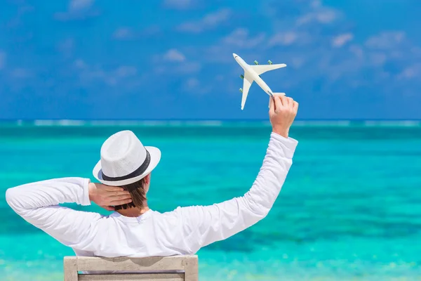 Young man with miniature of an airplane at tropical beach — Stock Photo, Image