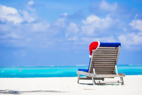 Sun chair lounge with red Santa Hat on tropical white beach and turquoise water — Stock Photo, Image