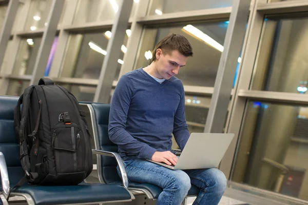 Havaalanında sandalyede otururken laptop ya da defter bilgisayar kullanarak iş adamı