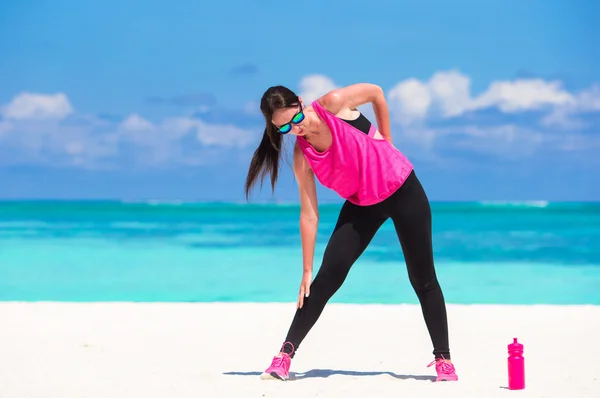 Zdravý sportovec žena pracující se dělá cvičení na tropické pláži s bílým v její sportovní — Stock fotografie
