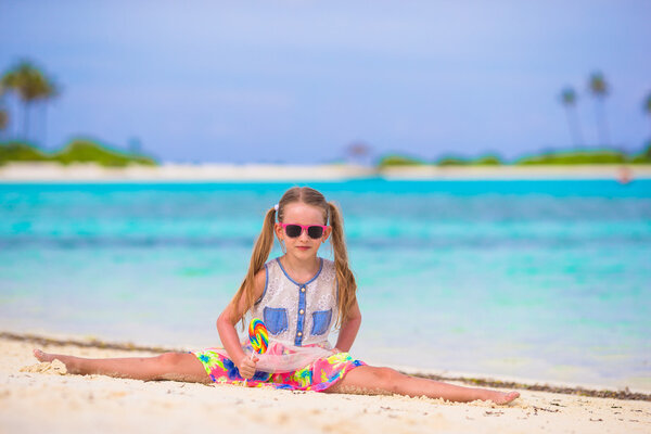 Adorable little girl have fun with lollipop on the beach