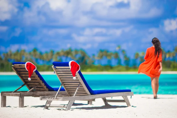 Due lettini con Babbo Natale rosso sulla spiaggia tropicale bianca con acqua turchese — Foto Stock