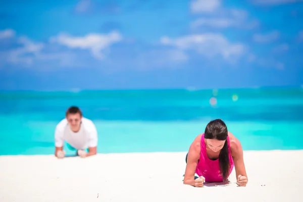 Para młoda fitness robi pompki podczas odkryty krzyż trening na tropikalnej plaży — Zdjęcie stockowe