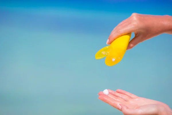 Ženské ruce s suncream láhev pozadí modré moře — Stock fotografie