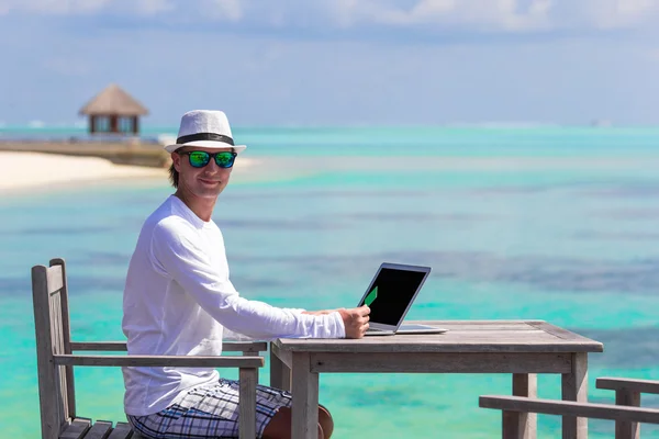 Young man with computer in outdoor cafe at summer vacation — Stock Photo, Image