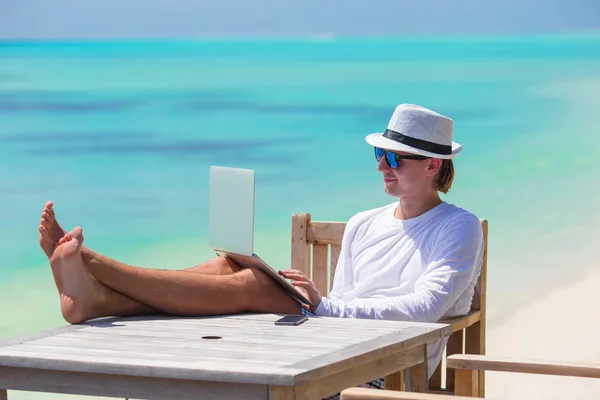 Hombre joven con tableta en la playa tropical — Foto de Stock