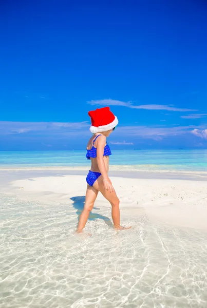 Menina em Santa chapéu na praia durante as férias — Fotografia de Stock