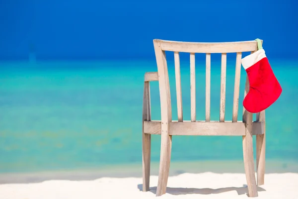 Czerwony kapelusz santa na krzesło na tropikalnej plaży biały — Zdjęcie stockowe