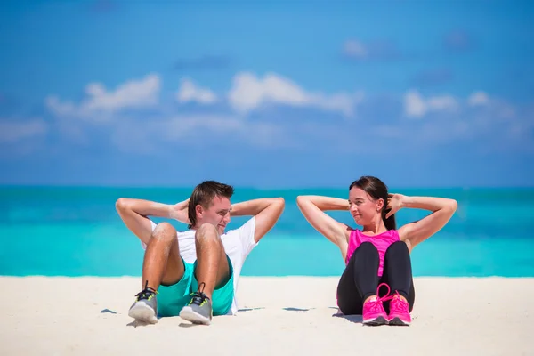 Para młoda fitness robi siedzieć ups na plaży biały — Zdjęcie stockowe