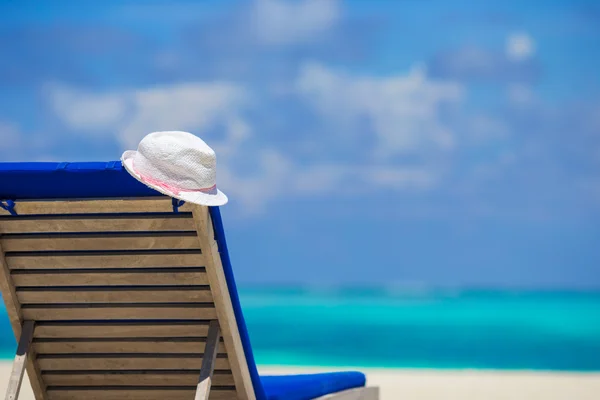 在热带沙滩休闲椅上的白帽子 — 图库照片