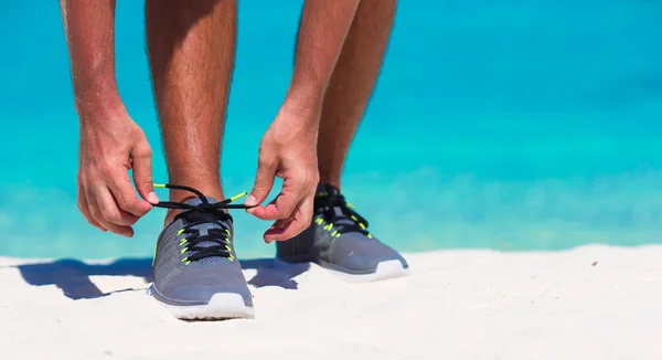 Joven corredor masculino preparándose para comenzar en la playa blanca — Foto de Stock