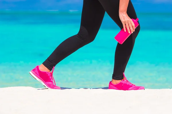 Zbliżenie kobiece nogi w trampki na białej, piaszczystej plaży — Zdjęcie stockowe