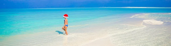 Meisje in Kerstman hoed op het strand tijdens vakantie — Stockfoto