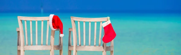 Boże Narodzenie czerwony i Santa Hat na krzesło na tropikalnej plaży biały — Zdjęcie stockowe