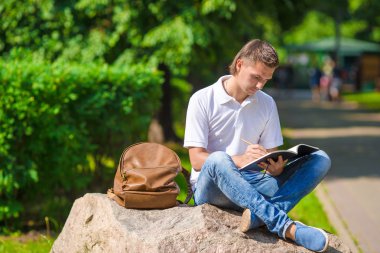 defter ve sırt çantası ile parkta genç öğrenci