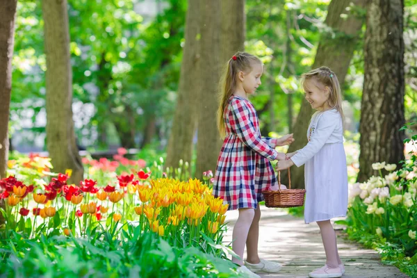 Little adorable girls walking in lush garden of tulips — Stock Photo, Image