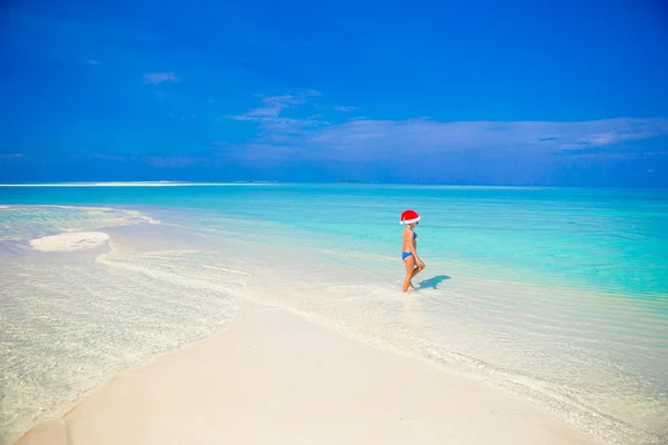 Niña en el sombrero de Santa en la playa durante las vacaciones — Foto de Stock