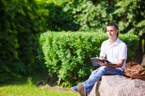 Junger Mann studiert für College-Prüfung im Park — Stockfoto