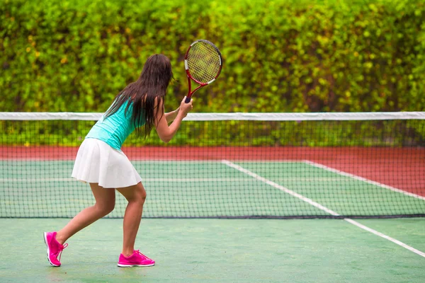 Jovem mulher ativa jogando tênis em férias tropicais — Fotografia de Stock