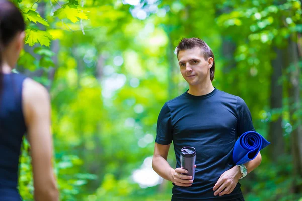 Correr pareja activa tener un descanso con estera y botella de agua al aire libre en el bosque —  Fotos de Stock