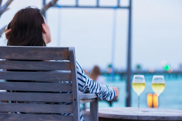 Junges Mädchen mit einem Glas Weißwein im Café am Abend — Stockfoto