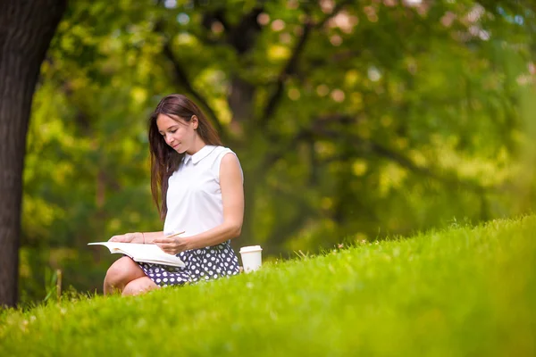 Junge Frau entspannt sich bei Kaffee im Park und liest ein Buch — Stockfoto